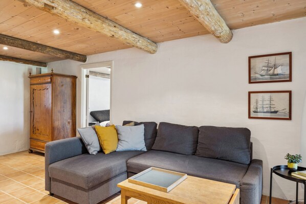 A living room with a grey sofa, wooden cabinet, and two framed pictures on the wall.