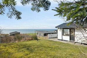 A modern house with a view of the sea, a grassy yard, and a white fence. - Enjoy the silence and stunning view over the sea (Spøttrup)