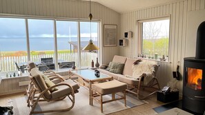 Ein gemütliches Zimmer mit Meerblick, einem Kamin und einer Essecke mit Gartenmöbeln.