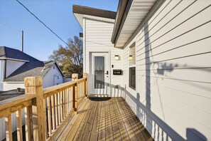 Una terraza de madera que conduce a un edificio blanco con una puerta marcada '518B'.