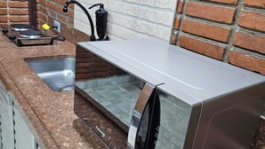 A kitchen with a stainless steel sink, a black faucet, and a built-in oven. - Friendly En-suite, to relax after a day of work / studies. (São Paulo)