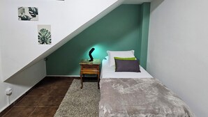 A bedroom with a sloped ceiling, a bed with pillows, a nightstand with a lamp, and wall art. - Friendly En-suite, to relax after a day of work / studies. (São Paulo)