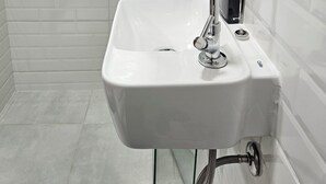 A bathroom with a white sink, chrome faucet, and a glass shower enclosure. - Friendly En-suite, to relax after a day of work / studies. (São Paulo)