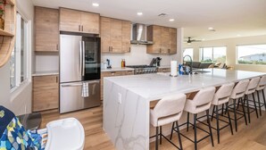 Una cocina moderna con armarios de madera, electrodomésticos de acero inoxidable y una isla grande con taburetes de bar.