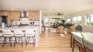 Una cocina moderna con una isla central, taburetes de bar y una zona de comedor con mesa y sillas.