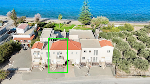 A coastal building with a red-tiled roof, surrounded by greenery and a beach. - Kalives Sand - Beachfront apartment (Chania)