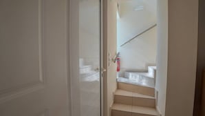 A hallway with a white door, a fire extinguisher, and a staircase with beige steps. - Kalives Sand - Beachfront apartment (Chania)