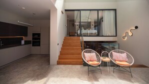 A modern kitchen with built-in appliances, a wooden staircase, and a seating area with wicker chairs. - VistaPort A (Bodrum)