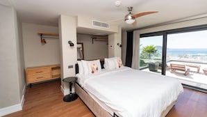 A modern bedroom with a large bed, a ceiling fan, a small bedside table, a wardrobe, and a balcony with a view of the sea. - VistaPort A (Bodrum)