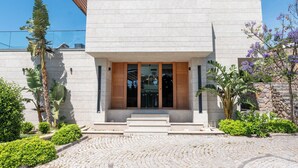 A modern building with a stone facade, large glass doors, and a paved entrance area with steps. - VistaPort A (Bodrum)