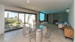 A modern living room with a glass dining table, a sofa, and a TV in the background. - VistaPort A (Bodrum)