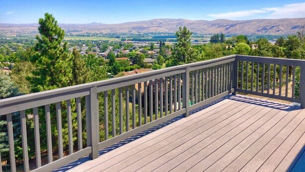 A wooden deck with a railing overlooking a valley with mountains in the distance. - Perfect 3-bedroom house with Gorgeous Views in Selah (Selah)