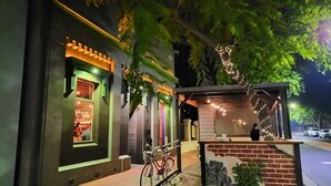 Un restaurante con fachada de ladrillo, mesas al aire libre y luces colgantes.