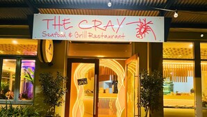 Exterior del restaurante Cray Seafood & Grill, con un letrero de neón y puerta de entrada de vidrio.