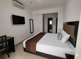 Una habitación de hotel moderna con una cama grande, un escritorio, un televisor de pantalla plana y una puerta que da a un baño.
