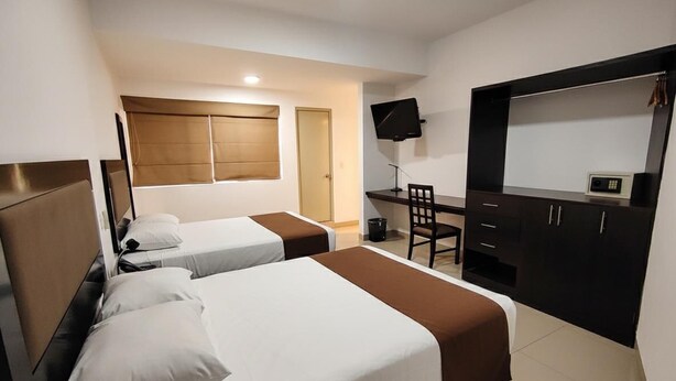 A hotel room with two beds, a desk with a computer, a TV, and a wardrobe. - Hotel Win & Win (Piura)