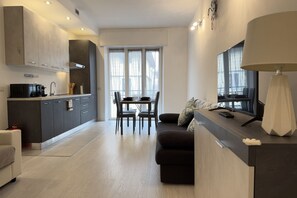 A modern kitchen with a dining area, a sofa, and a TV. - 10 Minutes' walk from the Railway Station (Alassio)