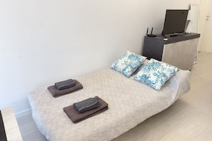 A bed with a textured cover, two pillows with a leaf pattern, and two folded towels. - 10 Minutes' walk from the Railway Station (Alassio)