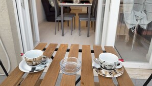 Un comedor con una mesa de madera, dos tazas blancas con platillos y un cenicero de vidrio transparente.