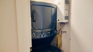 Eine kompakte Wasch- und Trockner-Kombination mit Bedienelementen und einem Netzkabel.