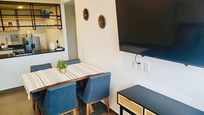 Ein kompakter Wohnraum mit Essbereich, Küchenzeile und einem an der Wand befestigten Flachbildfernseher.