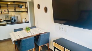 A compact living space with a dining area, kitchenette, and a flat-screen TV mounted on the wall. - Apart. Lafayette 02 2BE-2BA-1parking (Guadalajara)