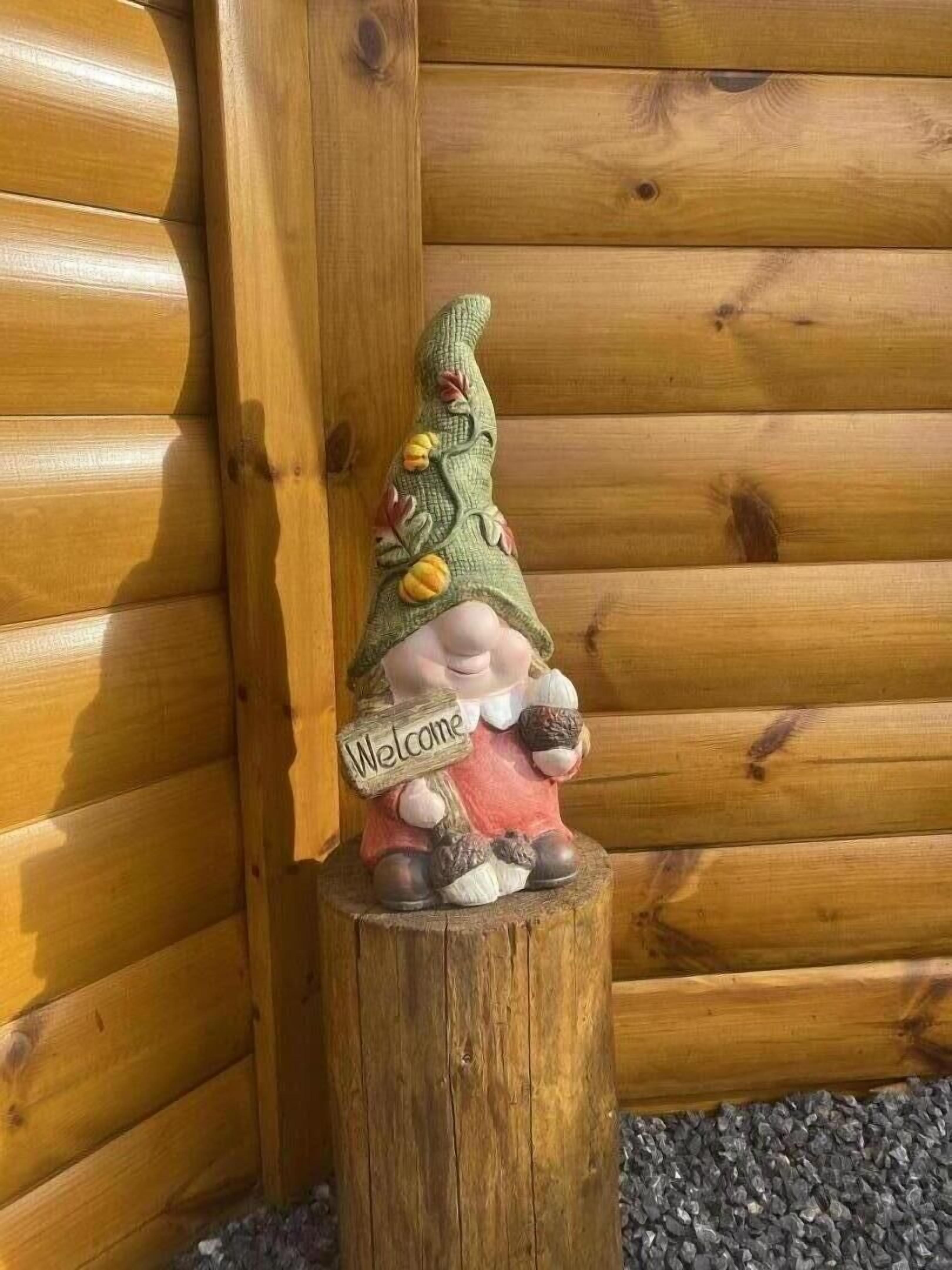 Eine Holzgnom-Figur mit einem 'Welcome'-Schild auf einem Baumstumpf.