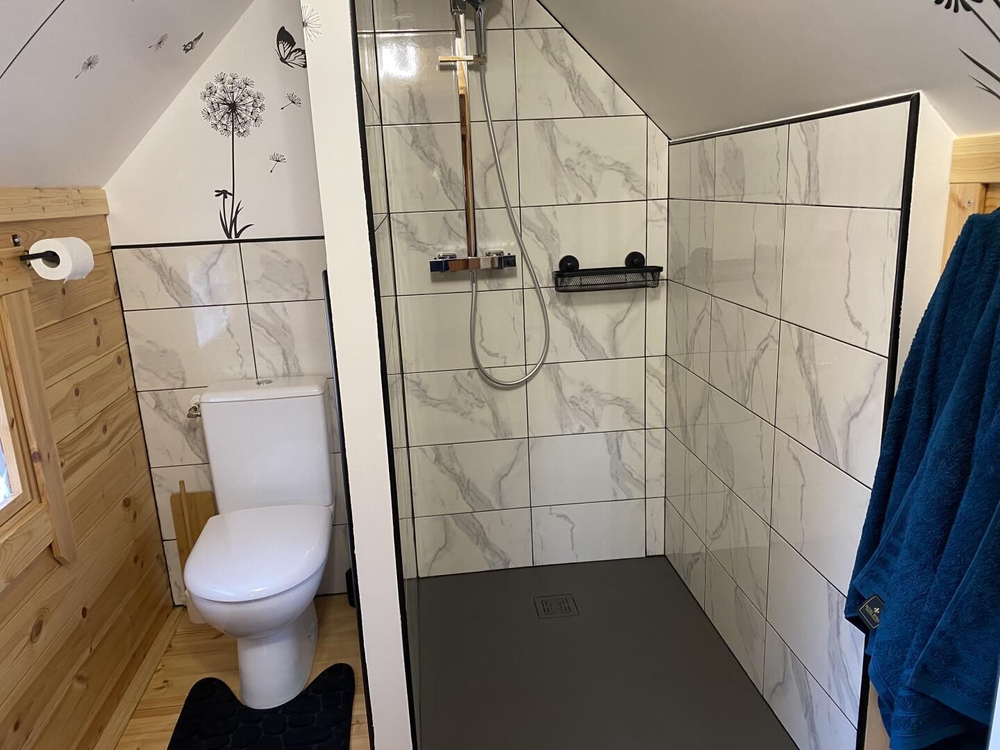 A compact bathroom with a toilet, a shower area, and a towel rack.