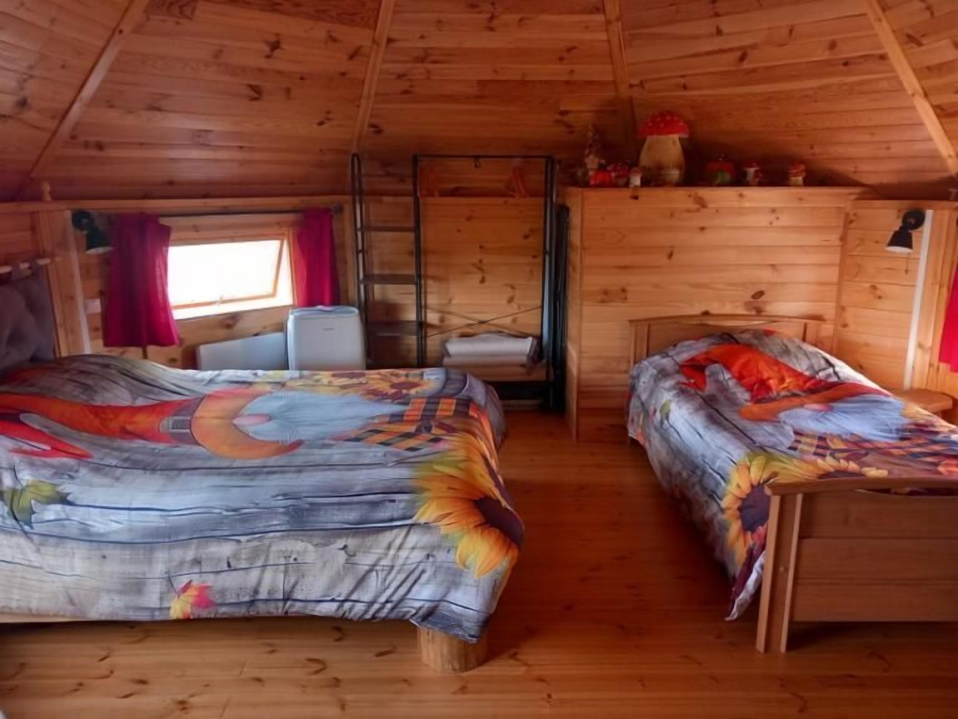 A cabin with two beds, a small table, a chair, and a window with curtains.