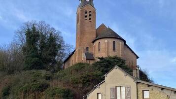 Une église dotée d’un haut clocher et d’un bâtiment plus petit situé sur une colline.