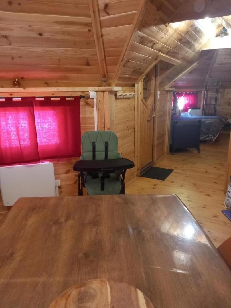 Un intérieur en bois avec une table à manger et des chaises, un radiateur et une fenêtre avec des rideaux.