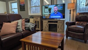 A living room with a leather sofa, a wooden coffee table, a television, and a fireplace.