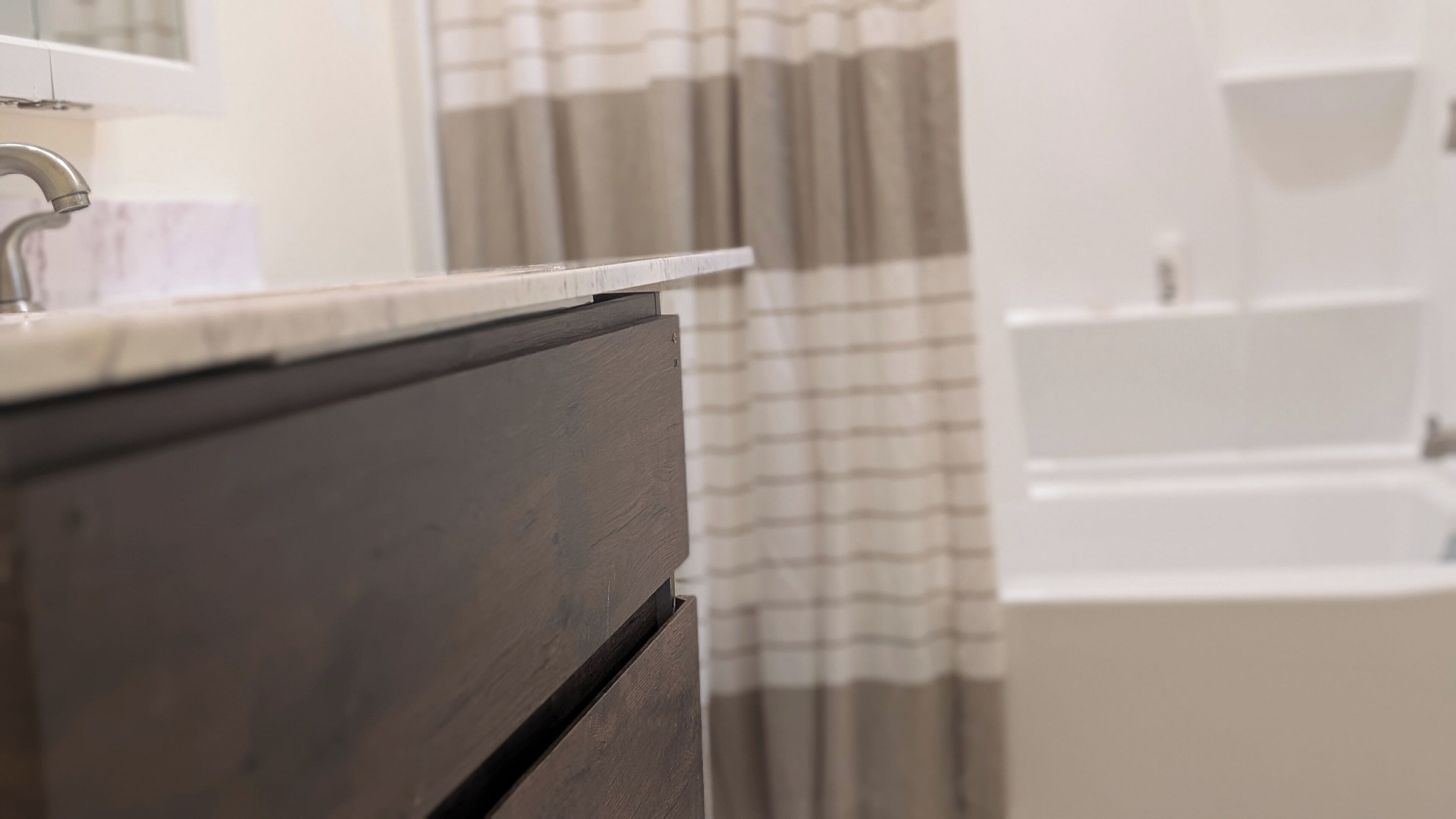 A bathroom with a dark wooden vanity, a white countertop, and a shower curtain.