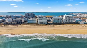 A coastal cityscape with modern buildings, a sandy beach, and a view of the sea. - Golden Surf 203 (Ocean City)