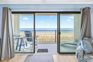 A room with a large sliding glass door leading to a balcony with a view of the beach. - Golden Surf 203 (Ocean City)