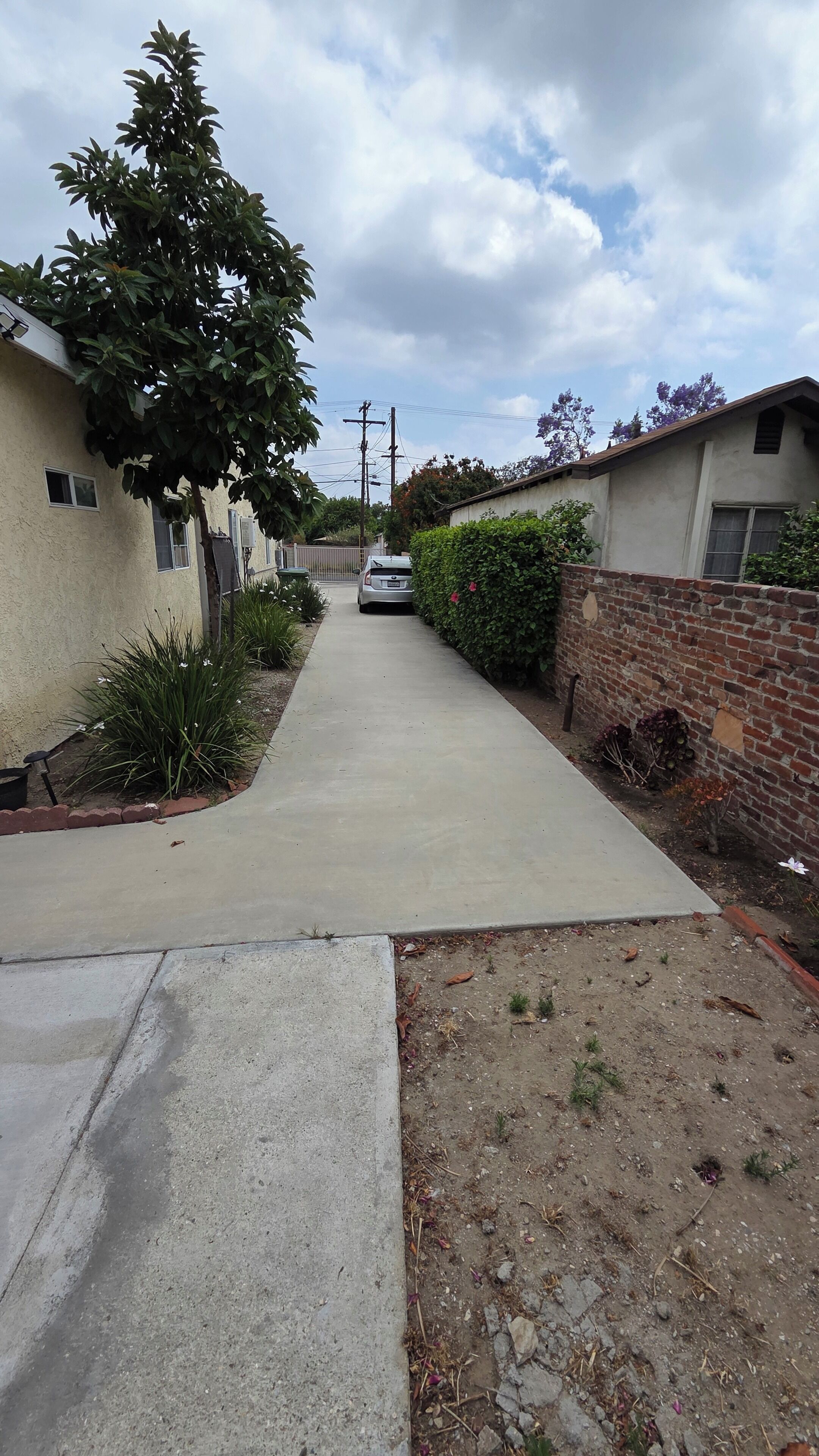 A residential street with houses, a sidewalk, and a parked car.