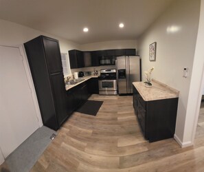 Una cocina moderna con gabinetes negros, electrodomésticos de acero inoxidable y encimera de mármol.
