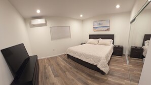 Una camera da letto con un letto, comodini, un mobile TV e un quadro appeso al muro.