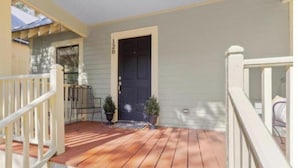 A porch with a wooden deck, a black door, and a white railing. - New listing! The Terra Cotta Bungalow with Firepit! (Athens)