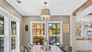 A dining area with a long wooden table, multiple chairs, and a chandelier. - Hartwell Haus with Dock & Playground (Fair Play)