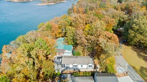 A house with a green roof, surrounded by autumn foliage and a lake. - Hartwell Haus with Dock & Playground (Fair Play)