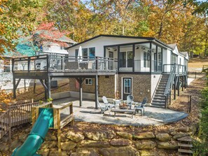 A two-story house with a balcony, outdoor seating area, and a slide. - Hartwell Haus with Dock & Playground (Fair Play)