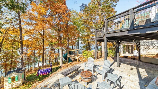 A patio with outdoor furniture, a fire pit, and a view of a lake surrounded by trees. - Hartwell Haus with Dock & Playground (Fair Play)