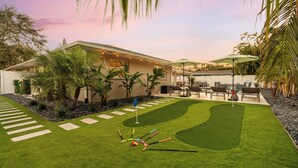 Un giardino curato con prato, un putting green e mobili da esterno.