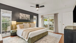 Una camera da letto con un letto, comodini, una ventola a soffitto e vista panoramica tramite una porta in vetro.