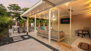 Area patio esterna con posti a sedere, piscina e logo Netflix.