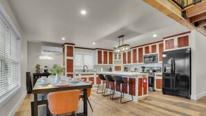 A modern kitchen with wooden cabinets, a black refrigerator, and a dining area with orange chairs.