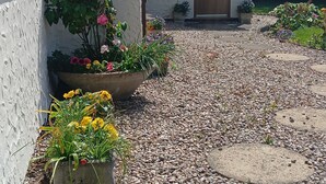 A building with a gravel driveway, potted plants, and a wooden door. - Park Cottage Bed & Breakfast near Burtonwood (Saint Helens)