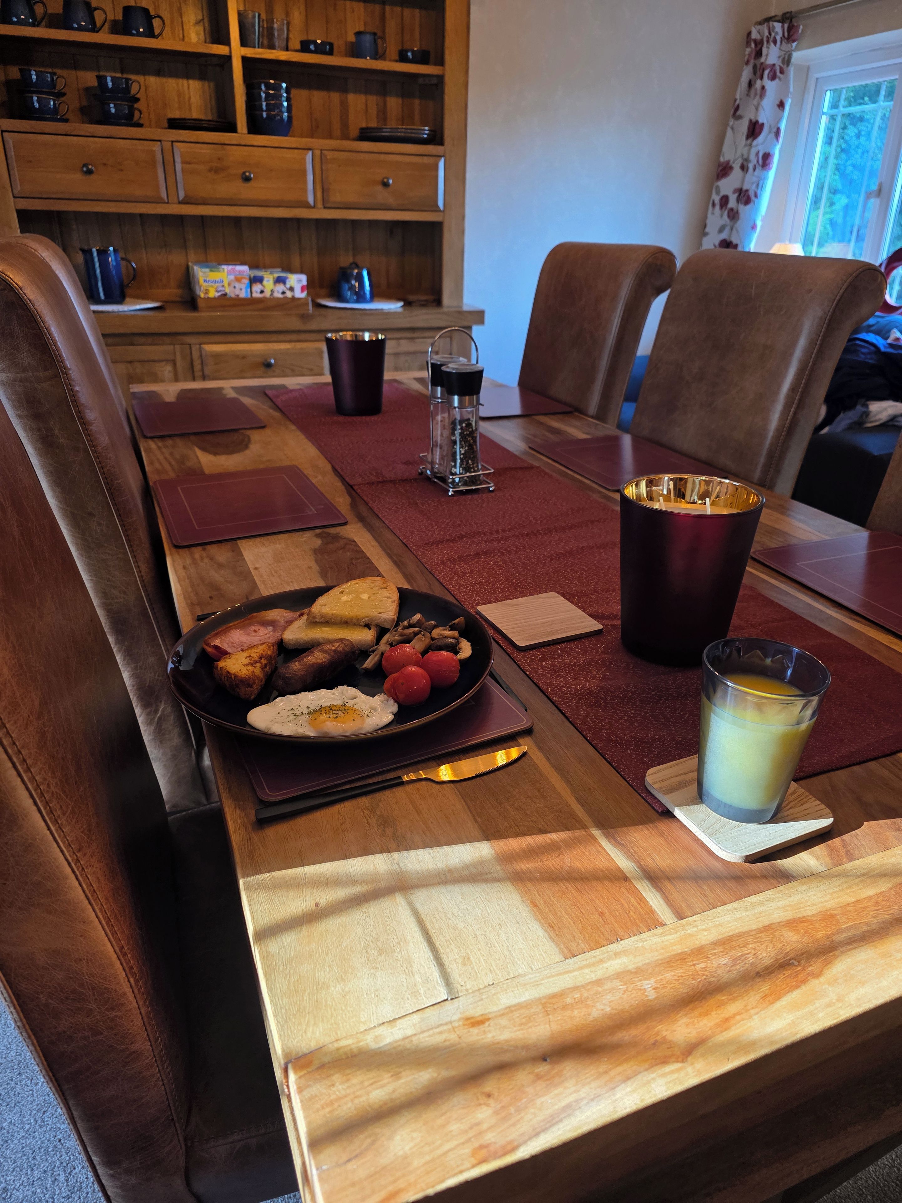 Ett matbord med en frukosttallrik, ett glas juice och en saltströare.