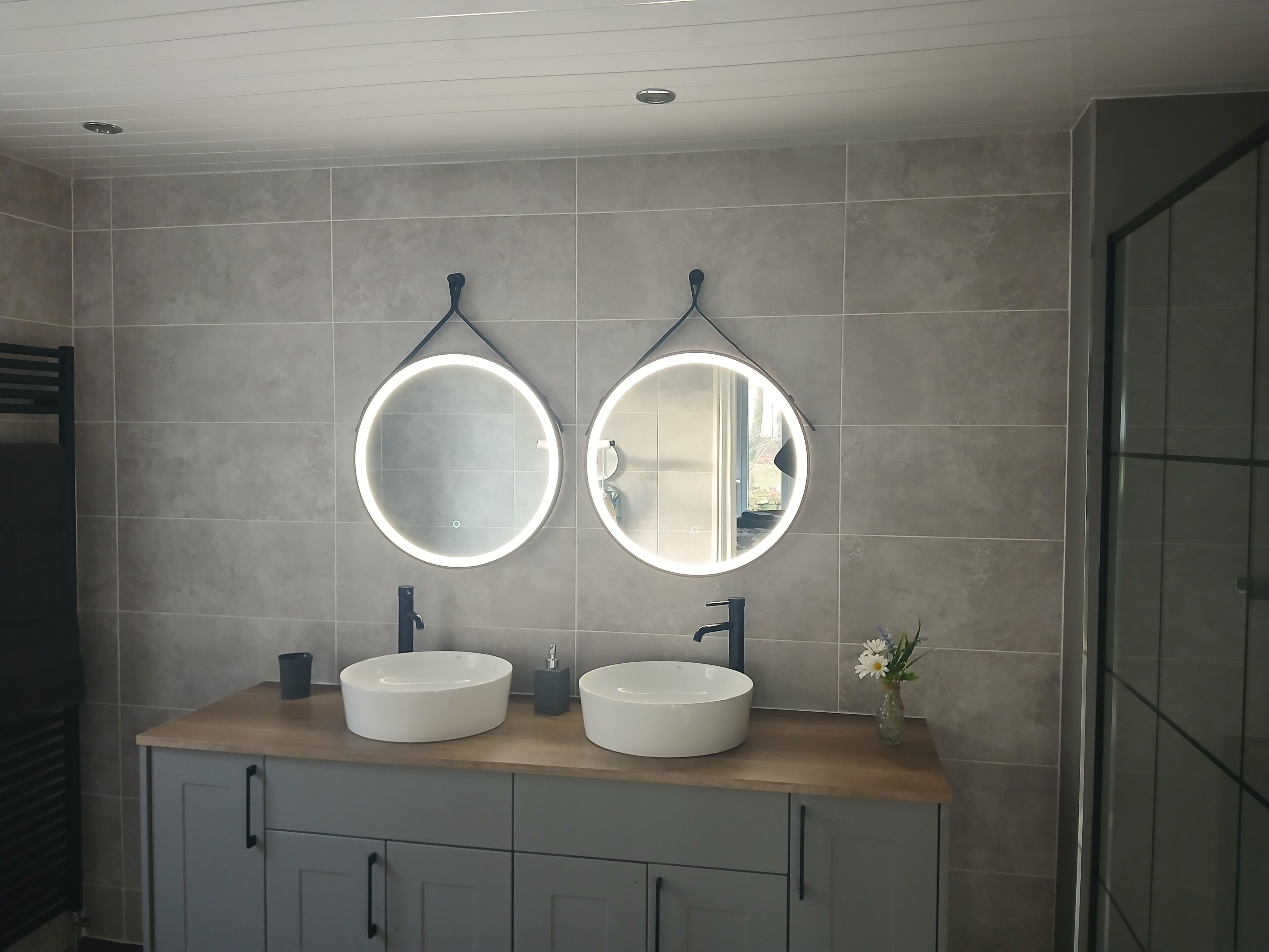 Un bagno con due specchi circolari, un lavabo doppio e un mobile con cassetti.